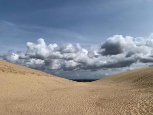 a sand dune with a cloudy sky in the background at 4 person holiday home in Løkken in Løkken
