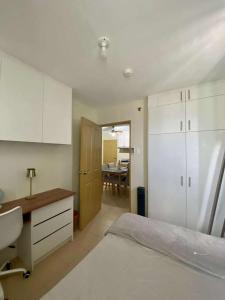 a bedroom with a bed and a desk and a table at Kaira's Condo at Marina Spatial 2 BR WIFI Netflix in Laguna