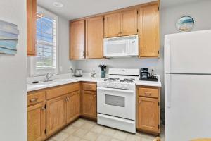 a kitchen with white appliances and wooden cabinets at Coastal Cutie in Oceano