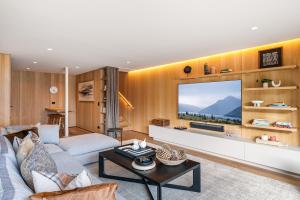 ein Wohnzimmer mit einem Großbildfernseher in der Unterkunft Luxury Away - Manaia Views-HotTub-FreeParking-BBQ in Queenstown