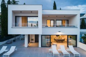 ein weißes Haus mit weißen Stühlen und einem Tisch in der Unterkunft Holiday home in Dramalj 45043 in Dramalj