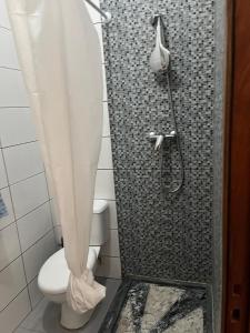 a bathroom with a shower with a toilet and a shower curtain at une chambre dépaysante in Tarrafal