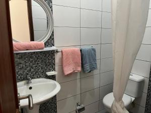 a bathroom with a sink and a toilet and a mirror at une chambre dépaysante in Tarrafal