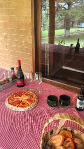 a table with a pizza and two glasses of wine at Tiny House in San Mateo Río Hondo