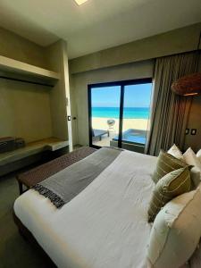 a bedroom with a bed with a view of the ocean at BeachFront with Jacuzzi Bahía Turquesa in La Ventana +64 photos