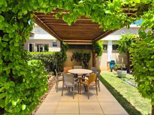 un patio con mesa y sillas bajo un seto en Cobertura Duplex - Luxo com Jacuzzi e 3 Suítes, en Aquiraz