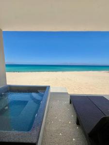 een zwembad met strand op de achtergrond bij Beachfront Luxury Condo Private Jacuzzi Ocean Views in La Ventana