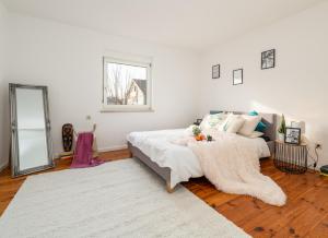 Un dormitorio blanco con una cama y un espejo. en Nice 65m2 apartment in central Dachau, en Dachau