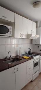 een witte keuken met een spoelbak en een magnetron bij Céntrico, de un dormitorio con cochera in Bahía Blanca