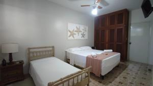 a bedroom with two beds and a ceiling fan at Pousada Mahalo in Guarujá