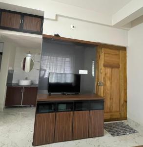 a living room with a television and a door at Yashaswi Residency - G001 in Manipala