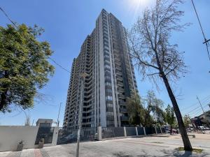 un edificio alto en una calle con un árbol en Loica Host - Smart, en Santiago