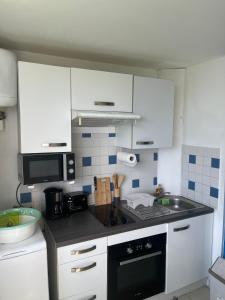 a kitchen with white cabinets and a stove top oven at Studio between Sea and Mountain in Le Diamant