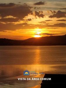 a sunset over a body of water with the sun setting at Casa Maria Mar in São José
