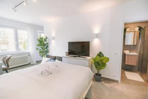 een witte slaapkamer met een groot wit bed en een televisie bij Stylish Studio in the Heart of Luxembourg City in Luxemburg