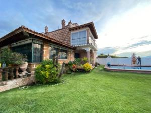 une maison avec une pelouse verte devant l'eau dans l'établissement Casa Vergel, à Temixco
