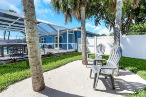 two chairs and palm trees in front of a house at Marco Island Pool, Spa Getaway Fenced Pet Friendly in Marco Island