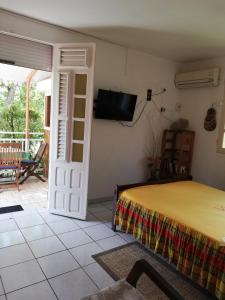 a room with a bed and a tv on the wall at Studio Griyav- dans villa les Polycias in Sainte-Luce