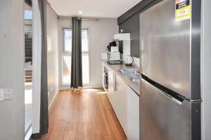 a kitchen with a stainless steel refrigerator and a wooden floor at Stylish Studio 1x1 Walk to CBD in Port Hedland