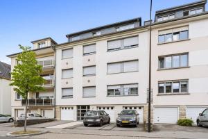 an apartment building with cars parked in a parking lot at Modern Limpertsberg Studio Near City Center in Luxembourg +12 photos