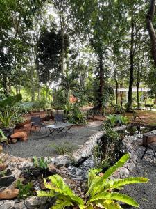 einen Garten mit 2 Stühlen, einem Tisch und Bäumen in der Unterkunft VANESSA'S GARDEN Restaurant & Bungalow in PhumÄ­ AnlÃ³ng Svay