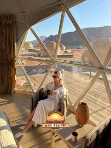 a woman sitting in a chair in front of a window at WADI RUM NEOM lUXURY CAMP in Wadi Rum