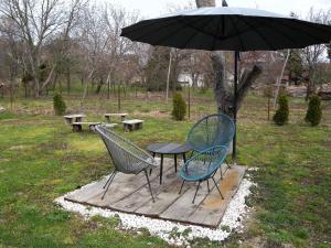 two chairs and a table under an umbrella at Apartments in Balatongyörök 34590 in Balatongyörök