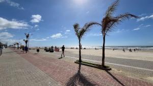 a person walking on the beach with palm trees at Nova cabana com jacuzzi perto do mar in Arroio do Silva