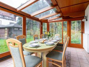 comedor con mesa en un salón acristalado en Landhaus am Waldrand, en Oberndorf in Tirol