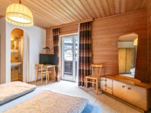 Un dormitorio con una cama, un escritorio y un televisor. en Landhaus am Waldrand, en Oberndorf in Tirol
