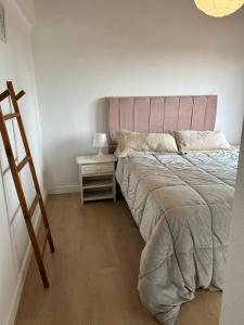 a bedroom with a bed with a pink headboard and a side table at aba casa estudio in Pinamar