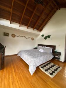a bedroom with a large bed and a wooden floor at Cabaña campestre Villa Maria in Tuta
