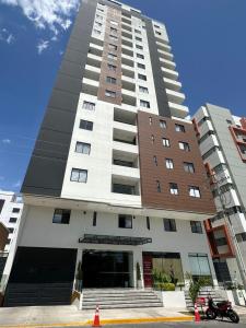 um prédio alto de apartamentos com uma motocicleta estacionada na frente em Monoambiente moderno y ubicación ideal em Cochabamba