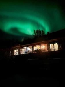 ein Haus mit den grünen Nordlichtern am Himmel in der Unterkunft Riverside Cottage in Lundur