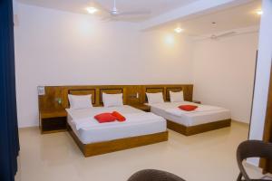 two beds in a room with white walls and red pillows at Ocean Light Mirissa in Mirissa