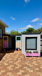 a house with colorful doors and flowers in a yard at Koala Cottage in Leongatha