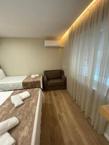 a room with a bed and a chair and a window at Hermes Petite Maison Hotel in Tirana