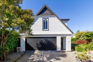 a white house with a garage at Chic Colourful Loft in the Heart of Merivale in Christchurch