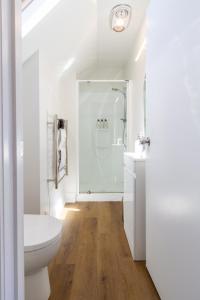 een witte badkamer met toilet en douche bij Chic Colourful Loft in the Heart of Merivale in Christchurch +16 foto's