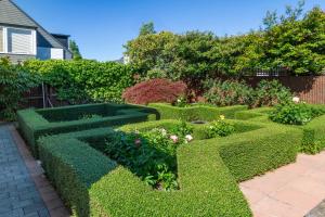 a garden with trimmed hedges and flowers at Chic Colourful Loft in the Heart of Merivale in Christchurch +16 photos