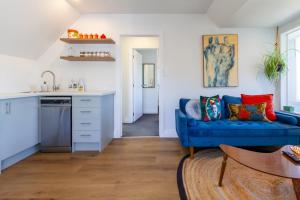 a living room with a blue couch and a kitchen at Chic Colourful Loft in the Heart of Merivale in Christchurch