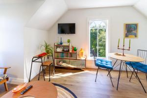 a living room with a table and chairs and a tv at Chic Colourful Loft in the Heart of Merivale in Christchurch