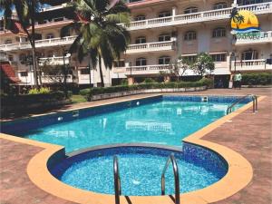 a large swimming pool in front of a building at Goa Beach Apartment in Colva