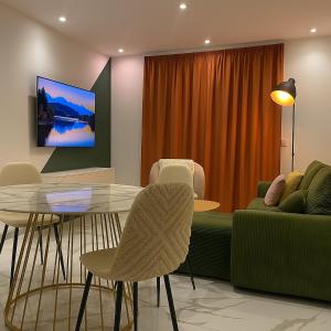 een woonkamer met een bank, een tafel en stoelen bij Chambre privée design, 8 min du Parc des Prince et de Roland Garros et à 4 min du métro 9 in Boulogne-Billancourt