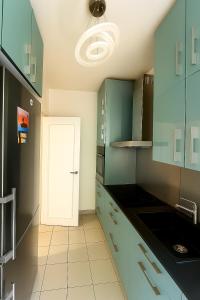 een keuken met groene kasten en een witte tegelvloer bij Chambre privée design, 8 min du Parc des Prince et de Roland Garros et à 4 min du métro 9 in Boulogne-Billancourt