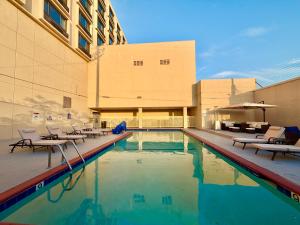 a swimming pool with chairs and a building at Lincoln Hotel Monterey Park Los Angeles in Monterey Park