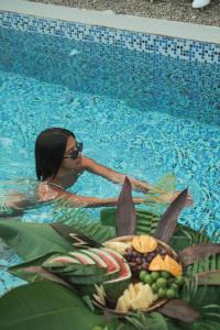 a woman in a swimming pool with a tray of food at Pahinga Villas Siargao in Libertad