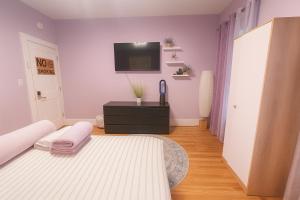 a bedroom with a bed and a tv on the wall at Lavender style Room in Geusthouse in New York