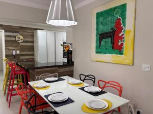 a dining room with a white table with red chairs at Apartamento completo, 200mts da praia de Pitangueiras in Guarujá