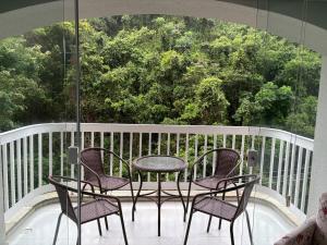 a patio with three chairs and a table on a balcony at Apartamento completo, 200mts da praia de Pitangueiras in Guarujá